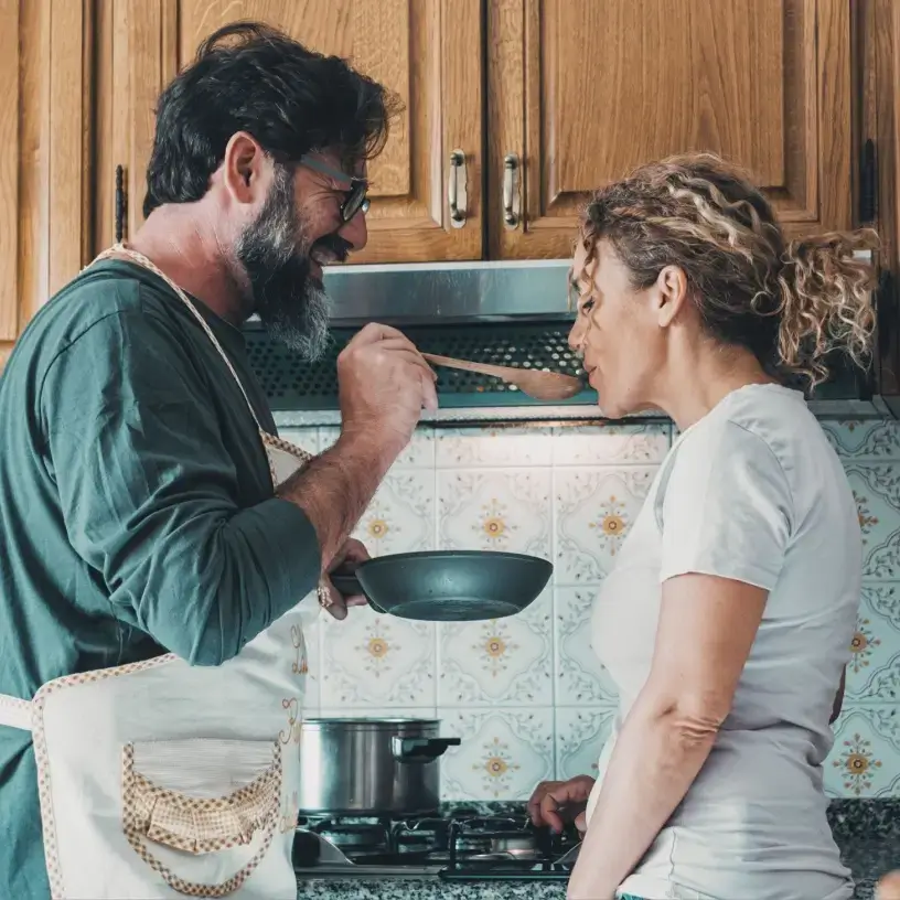 Happy couple cooking on gas stove